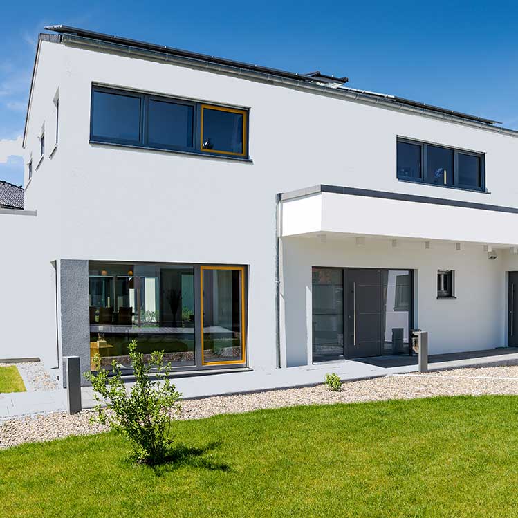 Ein modernes weißes Haus mit schwarzen Akzenten und Solaranlage.